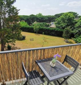 un tavolo e sedie su un balcone con giardino di Appartement Biscarrosse - Centre-ville, terrasse, au calme - agréable, tout confort - 4pers a Biscarrosse