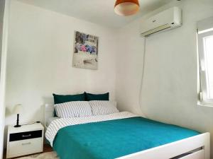 a white bedroom with a bed and a window at Novomesto in Igalo