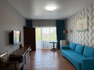 a living room with a blue couch and a tv at Villa Santorini in Zatoka