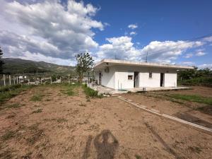 a building in a field next to a dirt field at Calma rooms in Përmet