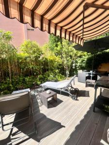 eine Terrasse mit Sonnenschirm, Bank und Tisch in der Unterkunft Le Nid d'amour Saint Cyr in Les Lecques