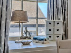 een tafel met een lamp, boeken en een raam bij Finest Retreats - Blue Monkey in Cawsand +13 foto's