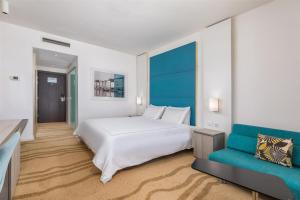 a bedroom with a white bed and a blue couch at Park Plaza Histria Pula in Pula