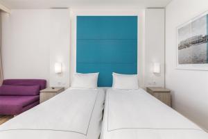 two beds in a room with a purple couch at Park Plaza Histria Pula in Pula
