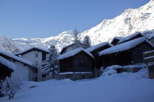 a group of buildings covered in snow with mountains in the background at Alpenhof in Saas-Fee
