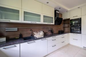 een keuken met witte kasten en een spoelbak bij Sunny Sobieszewo in Gdańsk +25 foto's