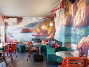 a restaurant with a large painting on the wall at Greet Hotel Nice Aéroport Promenade des Anglais in Nice