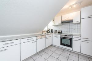 a white kitchen with white cabinets and appliances at Wenkendorf 52 MeErholung in Wenkendorf auf Fehmarn
