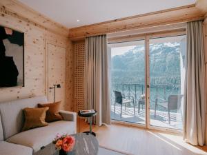 a living room with a couch and a large window at Kulm Hotel St. Moritz in St. Moritz