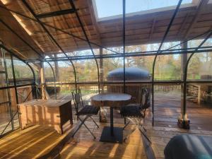 a glass house with a table and chairs in it at La terre du milieu 87 in Saint-Sulpice-les-Feuilles +48 photos