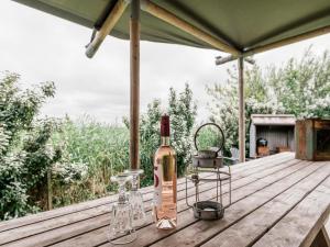 Una botella de vino y dos copas en una mesa de madera. en Beach Lodge Callantsoog near Dunes, en Callantsoog