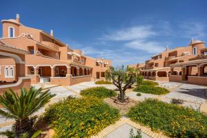 a courtyard of a building with a tree and flowers at DeCaNa Prestige Apartment - Gated Community Algarve in Porches
