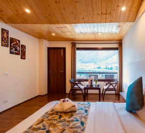 a bedroom with a bed and a table and a window at Himalayan Spurge Villa in Manāli
