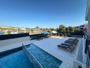 a swimming pool on the roof of a building with lounge chairs at SUENA HOTEL Çeşme in Çeşme