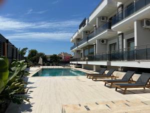 a swimming pool with lounge chairs next to a building at SUENA HOTEL Çeşme in Çeşme