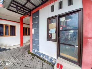 a red and white building with a glass door at RedDoorz Syariah at Homestay Bougenville near Taman Alun-Alun Kota Lamongan in Lamongan