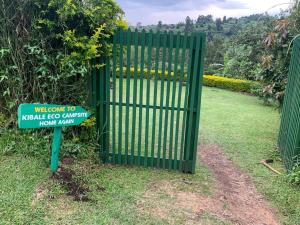 a green gate with a sign in front of it at Kibale Eco Campsite in Kabarole