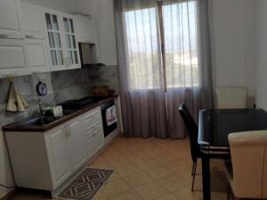 a kitchen with white cabinets and a table and a window at Karaj Apartment in Tirana