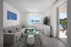 a white living room with a couch and a tv at Duka & Piko apartmani in Otok Lastovo