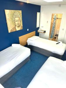 a room with three beds and a painting on the wall at The Regency Hotel in Blackpool