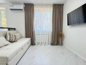 Una sala de estar con un sofá blanco y un televisor. en Квартира Новомоссковская, en Salor Bekati