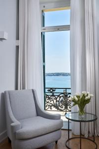a living room with a chair and a table and a window at Poseidonion Grand Hotel in Spetses