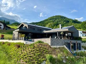 una casa en una colina con montañas al fondo en NEW! Apartment Alpinero 405 by we rent, en Piesendorf