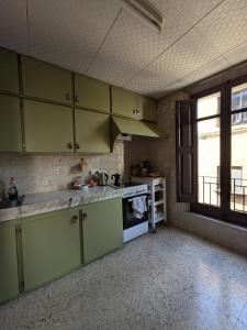 an empty kitchen with green cabinets and a window at L'Artesania - The Craft village house in Albí +23 photos