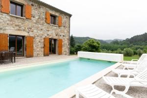a swimming pool with chairs and a house at Les Sources Gîte La Grange in Chambonas