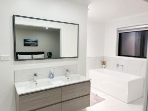 a bathroom with a sink and a tub and a mirror at 7th Heaven on Waikato River in Hamilton