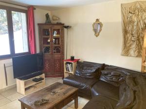 a living room with a leather couch and a table at Chalet Parc des Écrins in Le Petit-Parcher