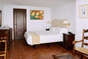 a bedroom with a white bed and a chair at Molino Del Santo in Benaoján
