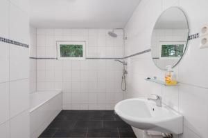 a white bathroom with a sink and a mirror at Familiehuis met Hottub + trekkershutten | 18 Pers. in Wilsum +7 photos