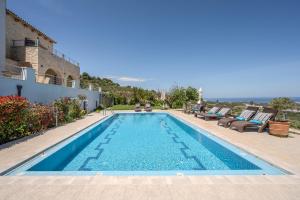 a swimming pool with chairs and a house at Arios Lux Villa in Ayía Paraskeví