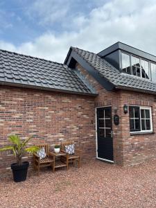 a brick house with two chairs and a table at B&B 'Op Eemdijk' in Eemdijk +10 photos
