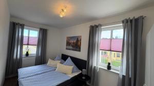 a bedroom with a bed and two windows at Ferienwohnung Fürstenberg - Spatz in Fürstenberg-Havel