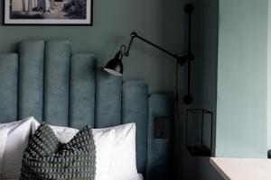 a bedroom with a bed with a blue headboard and a lamp at Quality Hotel Carlia in Uddevalla