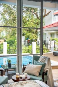 a living room with a view of a pool through windows at ELIVAAS Prive Suntuarios Casa Iris 4 BHK Getaway with Jacuzzi, Pvt Pool & Gazebo in Marna