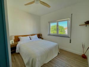 a white bedroom with a bed with a ceiling fan at Wild Souls Guesthouse in Ericeira