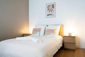 Un dormitorio con una cama con sábanas y almohadas blancas. en L'Arche d'Orléans, en Orléans