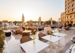 een patio in een hotel met tafels en stoelen bij InterContinental Doha Beach & Spa by IHG in Doha