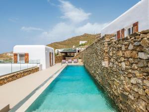 a swimming pool next to a stone wall at Villa Levi's in Mykonos