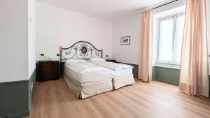 a bedroom with a white bed and a wooden floor at Residence la Limonera in Bellagio