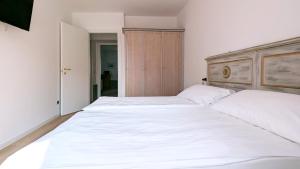 a bedroom with two white beds and a wooden headboard at Residence la Limonera in Bellagio