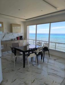 a kitchen with a table and chairs and the ocean at Appart Rafraf Sounine in Ibn Khaldoun
