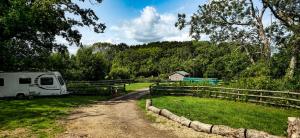 a camper parked on a dirt road next to a field at Springfield oaks Glamping Pod in Isle of Wight