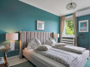 沃尔特湖畔韦尔登Ferienwohnung mit traumhaftem Seeblick的卧室里有一张床，蓝色的墙壁和一扇窗户