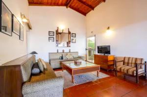 Una sala de estar con un sofá y una mesa de café. en Lennys Nainital Hills 3 BD Garden Villa with Cook, en Bhowāli