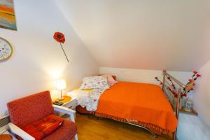 a small bedroom with a bed and a chair at Private Stone Cottage with Garden and BBQ in Gornji Proložac