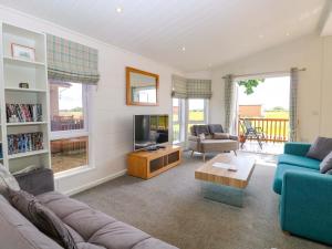 a living room with a couch and a tv at Oak Tree Holiday Lodge in Stowmarket